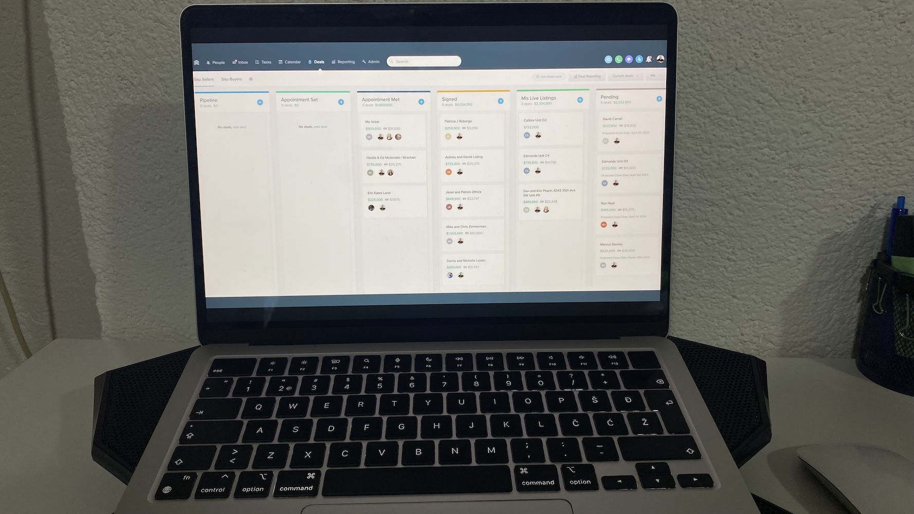 Laptop showing Follow Up Boss CRM deals pipeline with columns for pipeline stages, signed agreements, live listings, and pending deals.