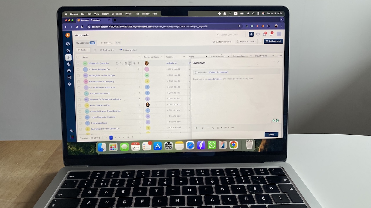Laptop screen displaying Freshsales contact management interface with accounts list and notes panel