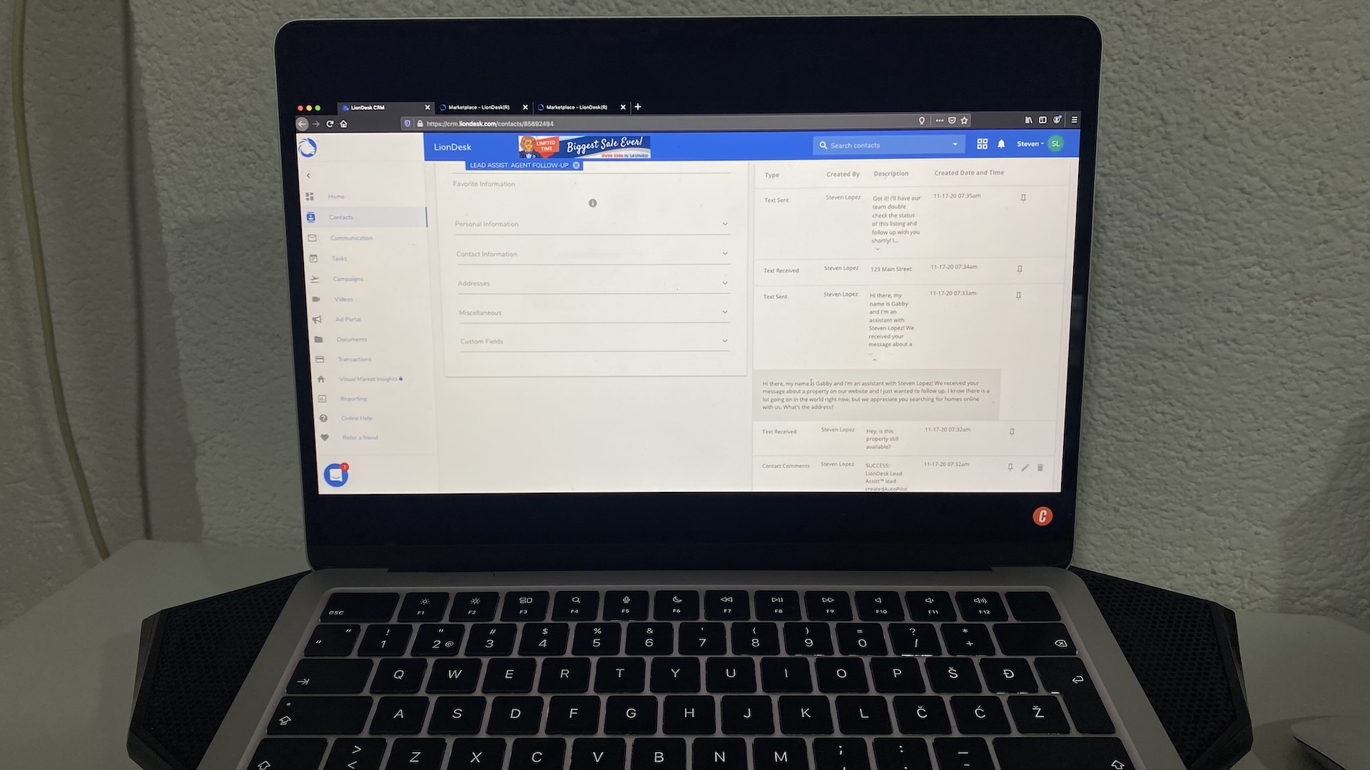 Laptop screen with LionDesk CRM open, showing contact details, personal info fields, and text message history.